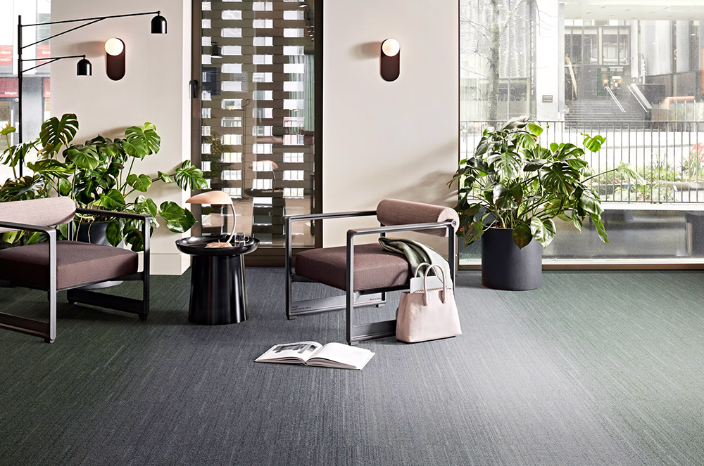 interior space with woven gradience tile flooring from green to light grey to dark grey and black with lots of plants and an armchair