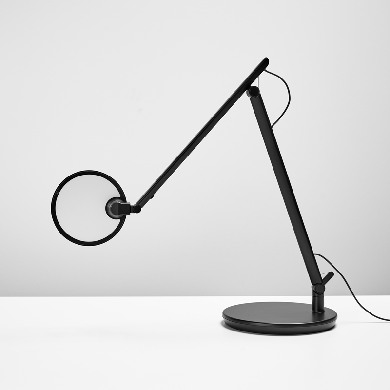 Nova task light in black color set on a white desk with a grey background