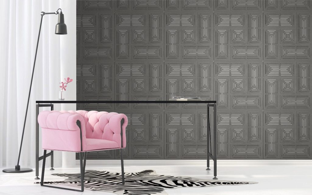 Interior space with dark grey muratto acoustic panels on the wall and a pink arm chair next to it with a light fixture above it and a carpet on the floor