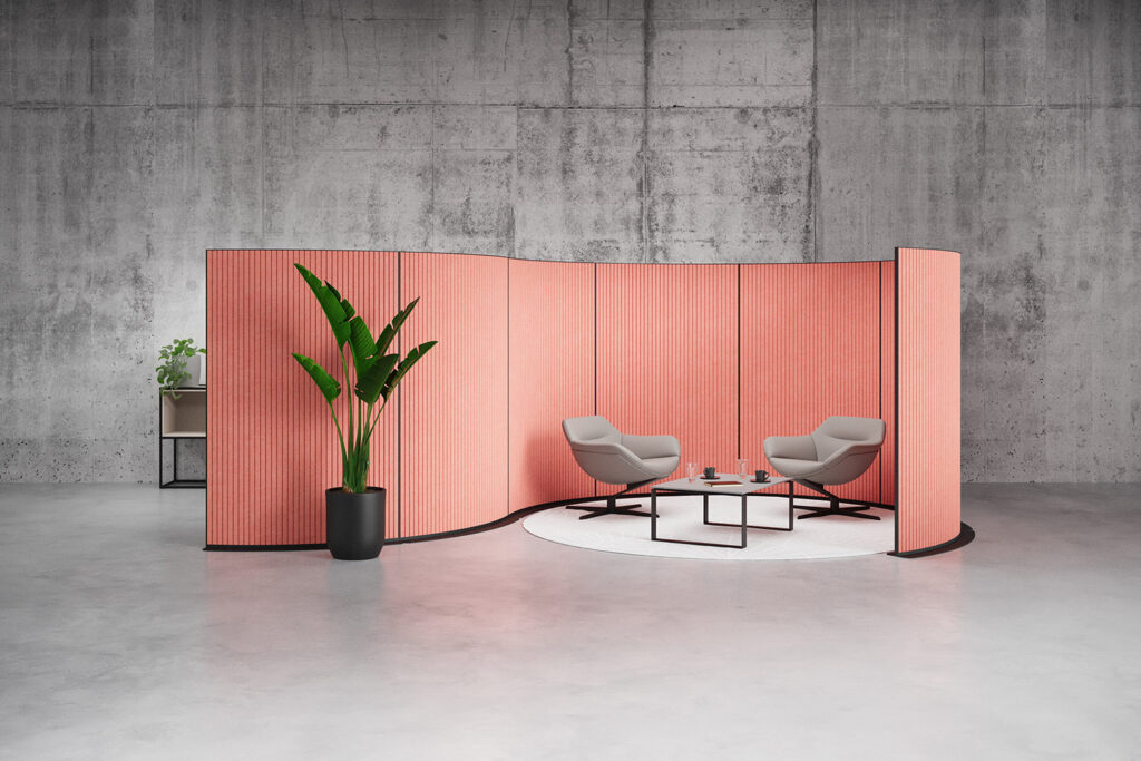 EchoCove Bow in salmon color in front of a cement wall surrounding two grey lounge chairs with a coffee table between them