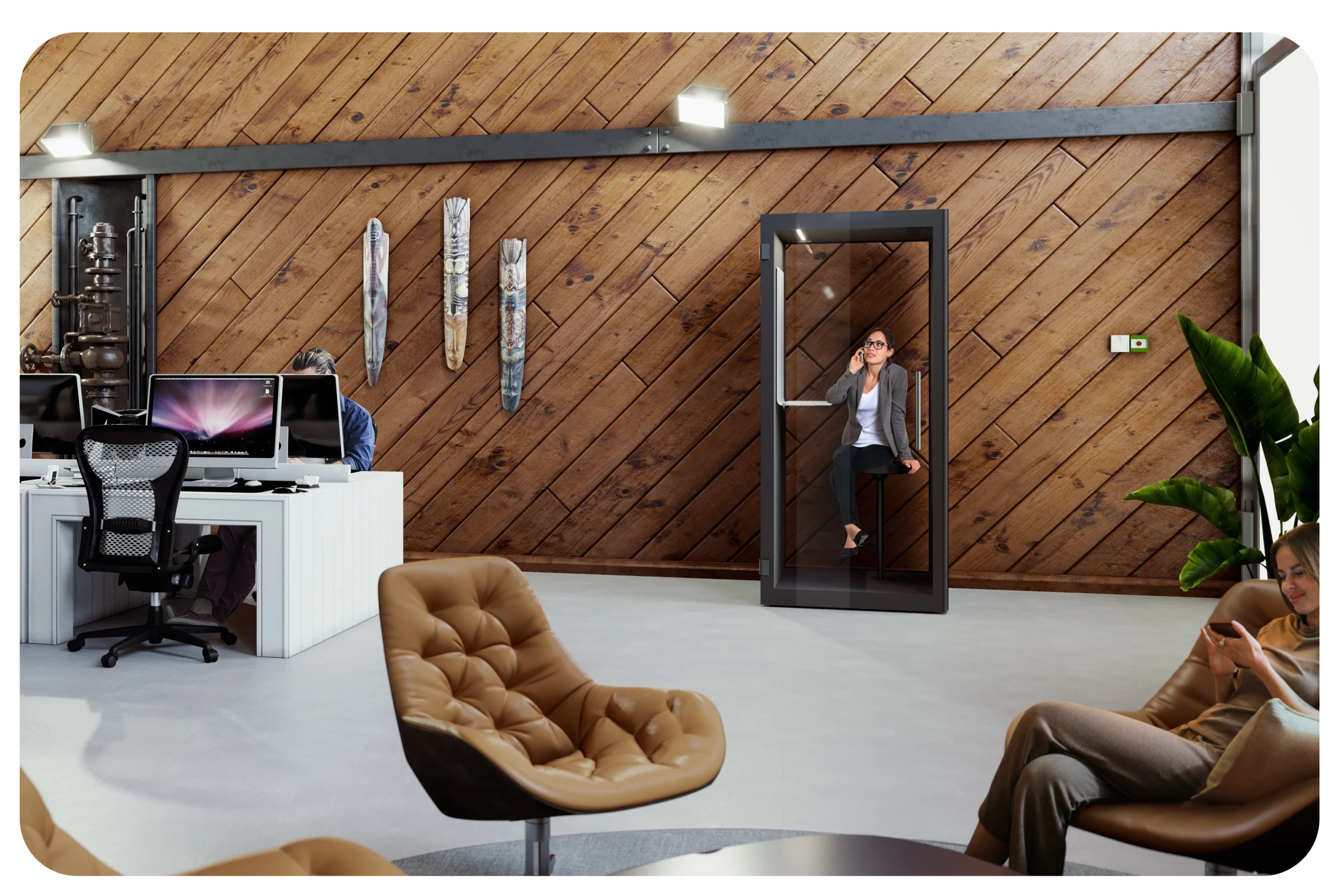 open plan office space with desk benches on one side and a small social area on the other. A phone booth is placed against a wall.
