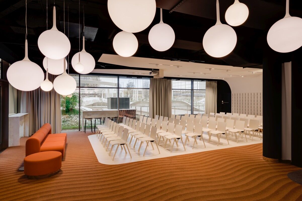 townhall meeting space with white mdd chairs and an orange mdd sofa in the front